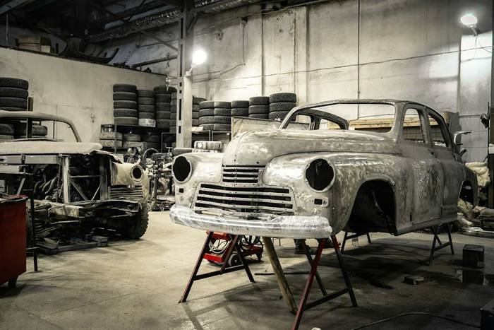 Bare metal classic car body on stands in a restoration shop