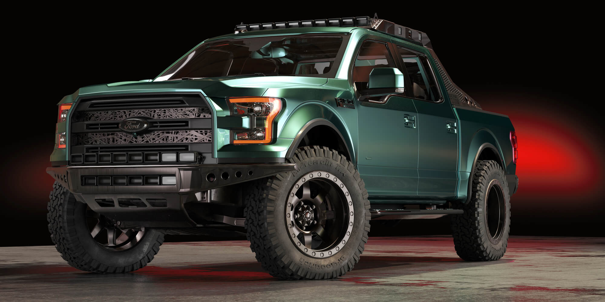 A green off-road pickup truck with large tires is parked indoors on a concrete floor, with a black background and red lighting behind it.