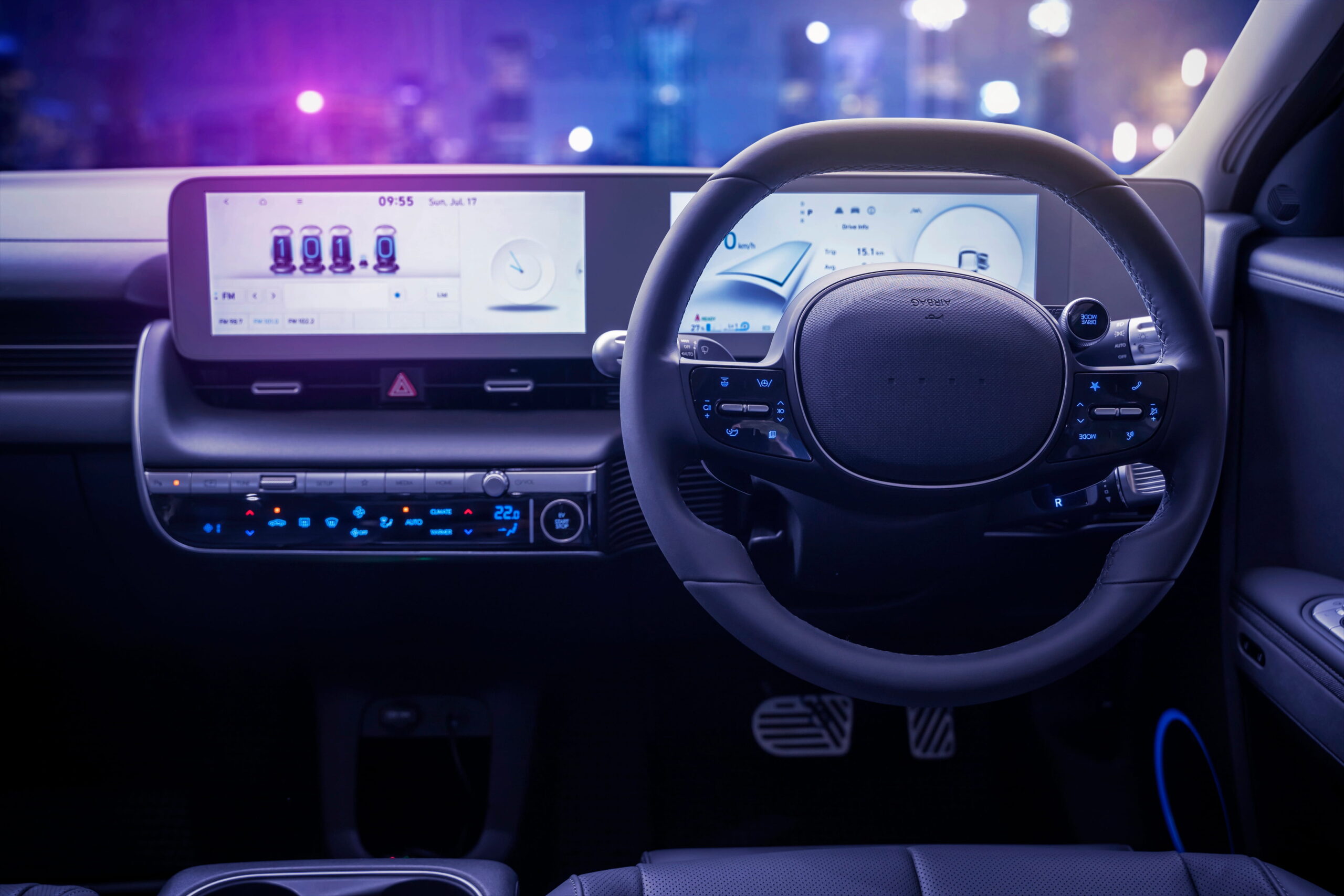 Car interior at night lit by purple and blue ambient lighting