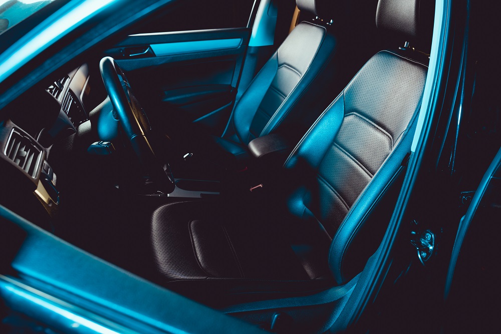 Car interior with leather seats lit by teal ambient lighting