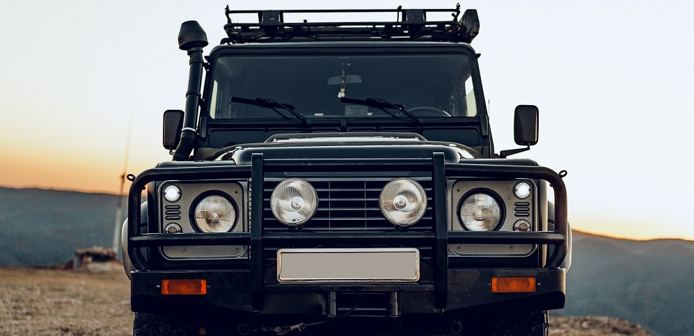 Front of a black off-road vehicle with a light bar at sunset
